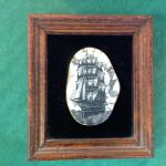 Framed scrimshaw of a sailing ship. Signed "Jamie 1984" on the front.